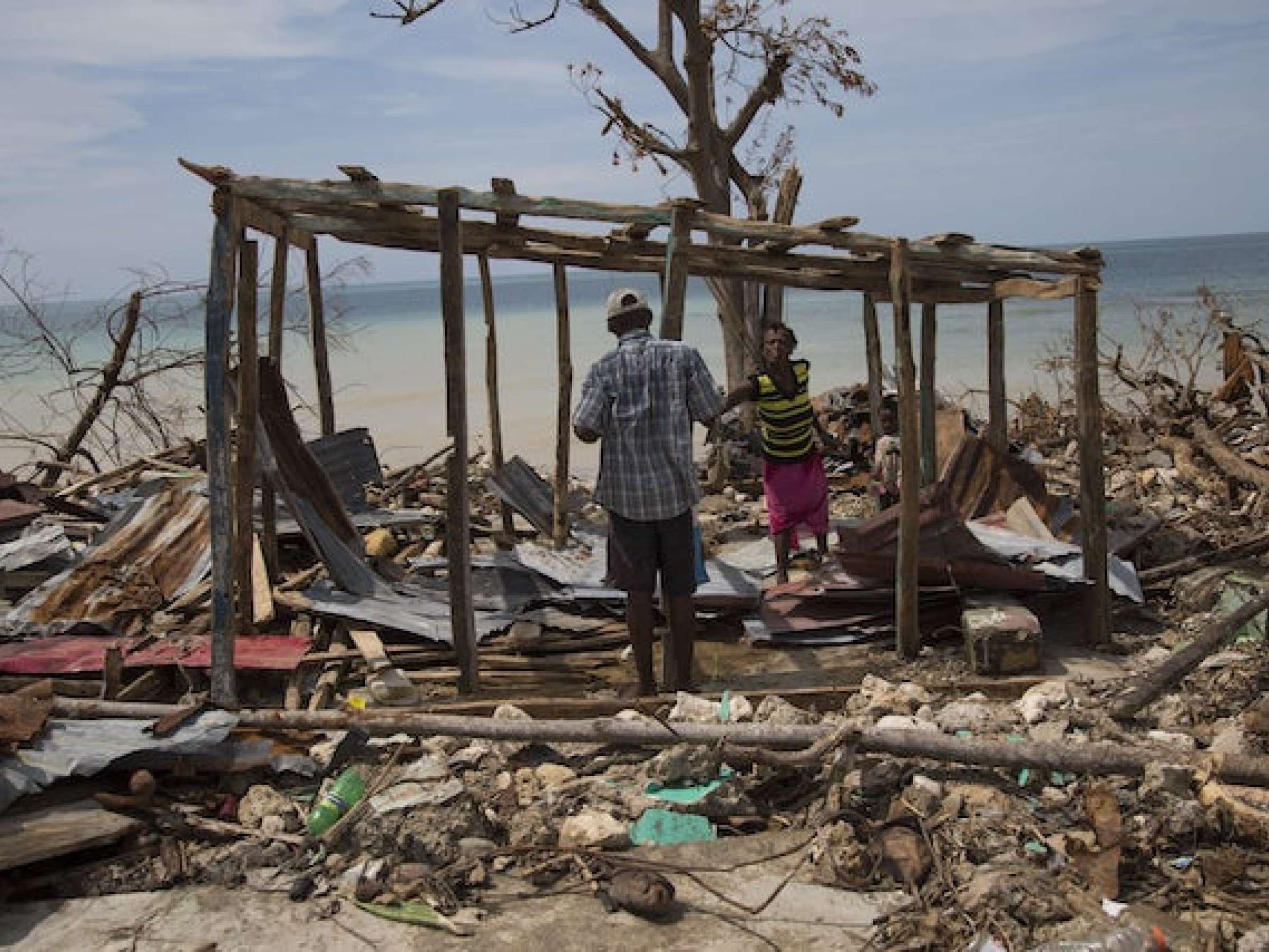 People in a destroyed house following Hurricane Matthew in Roche a Bateux, Haiti in October 2016