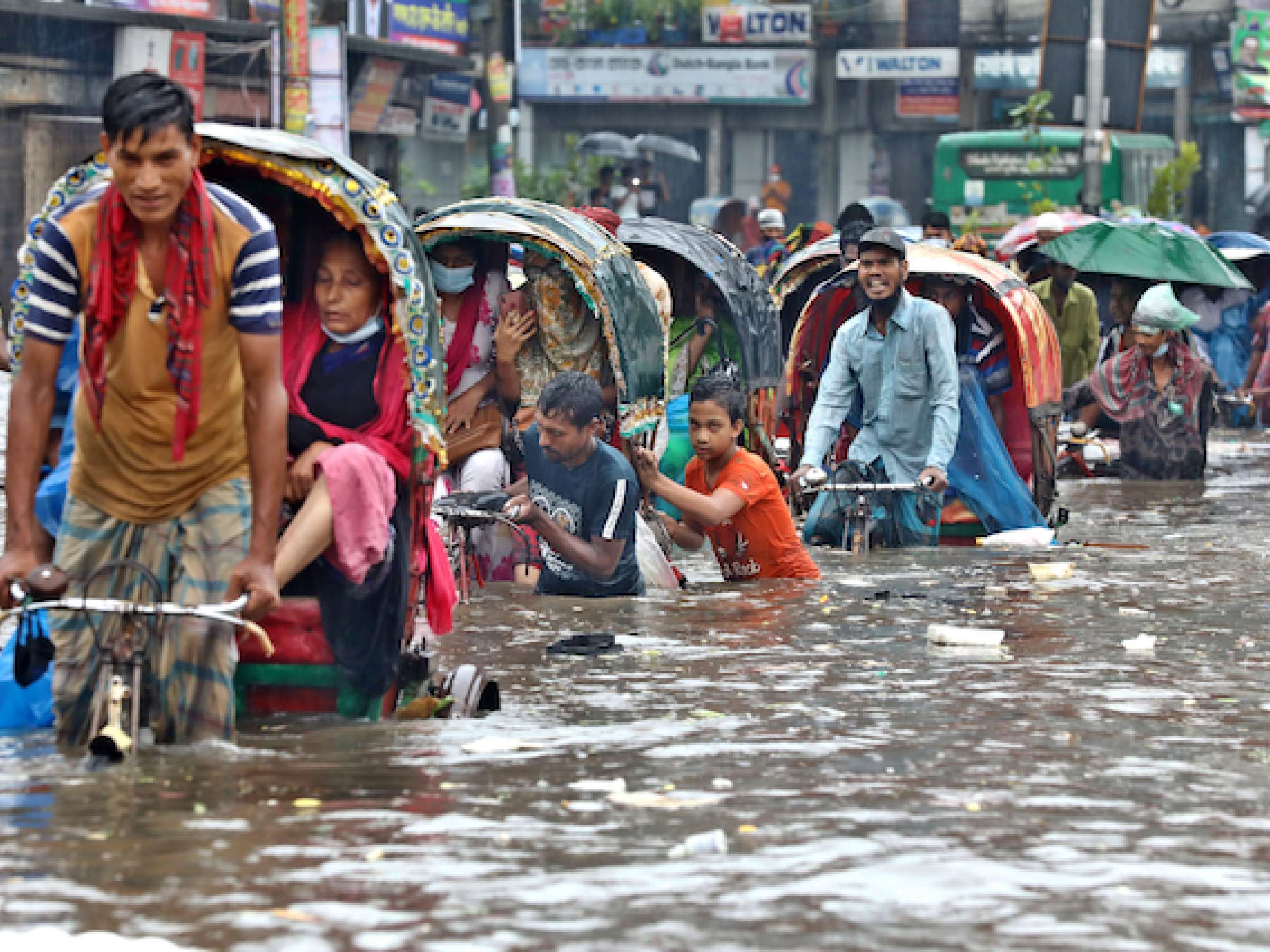 Vehicles try to drive through a flooded street in Dhaka.