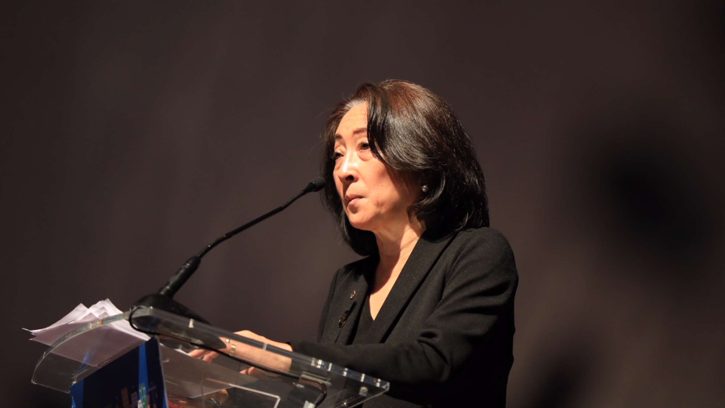 Mami Mizutori standing in front of a microphone delivering a speech