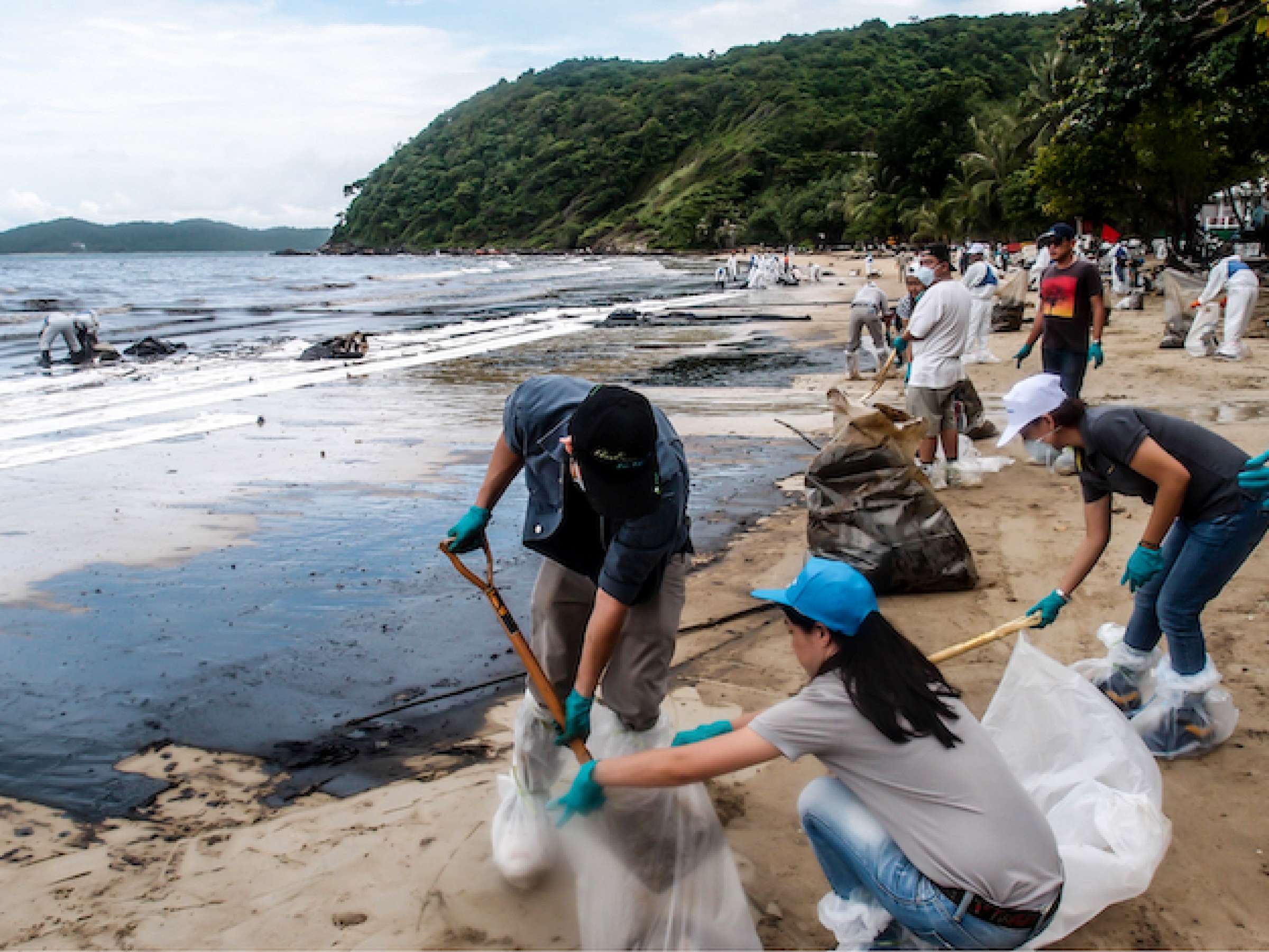 People clearing contaminated sand at the Aou Prow beach, Rayong, Thailand on Jul 31, 2013.