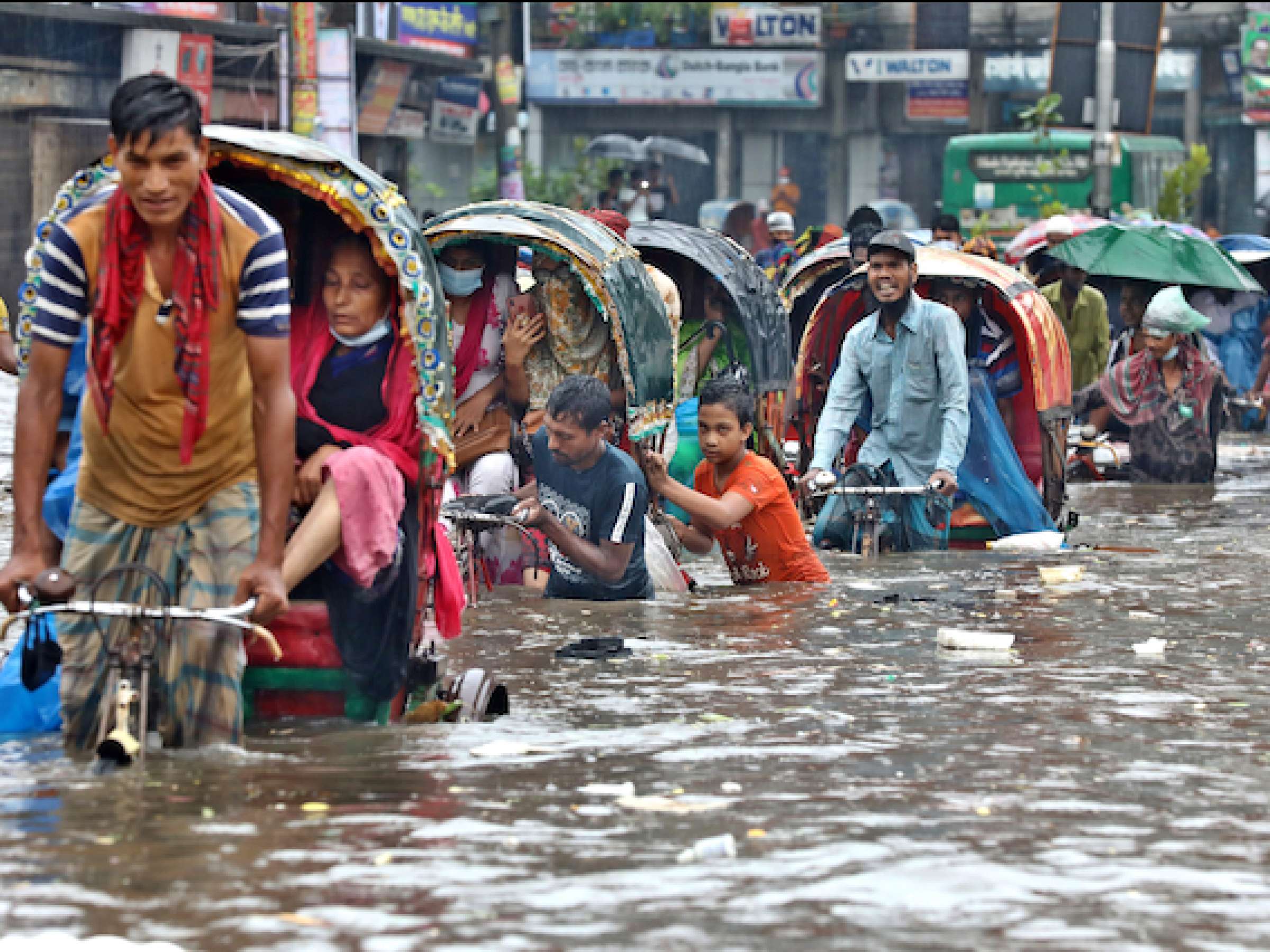 Vehicles try to drive through a flooded street in Dhaka.