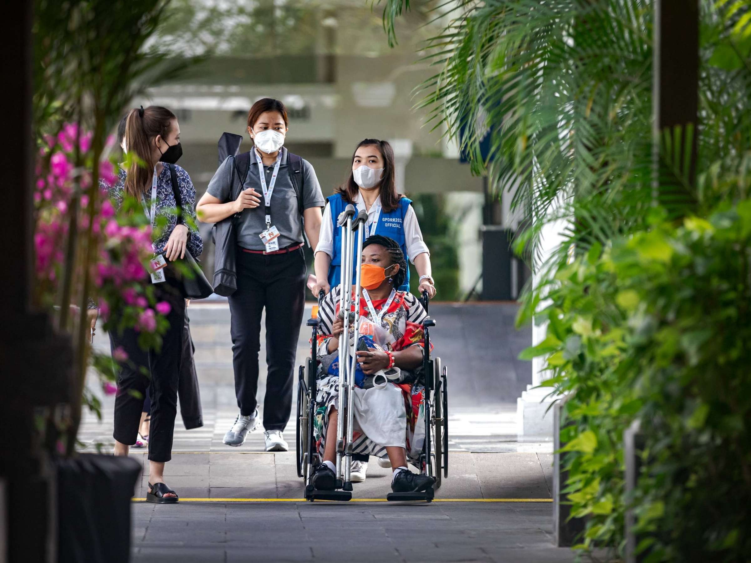 A woman being wheeled in a wheelchair at the 7th Global Platform for Disaster Risk Reduction, 27 May 2022, Bali, Indonesia