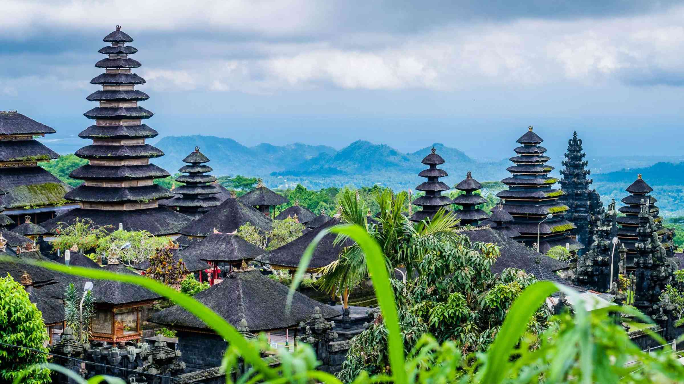 View of Balinese temples and greenery with mountains in the background