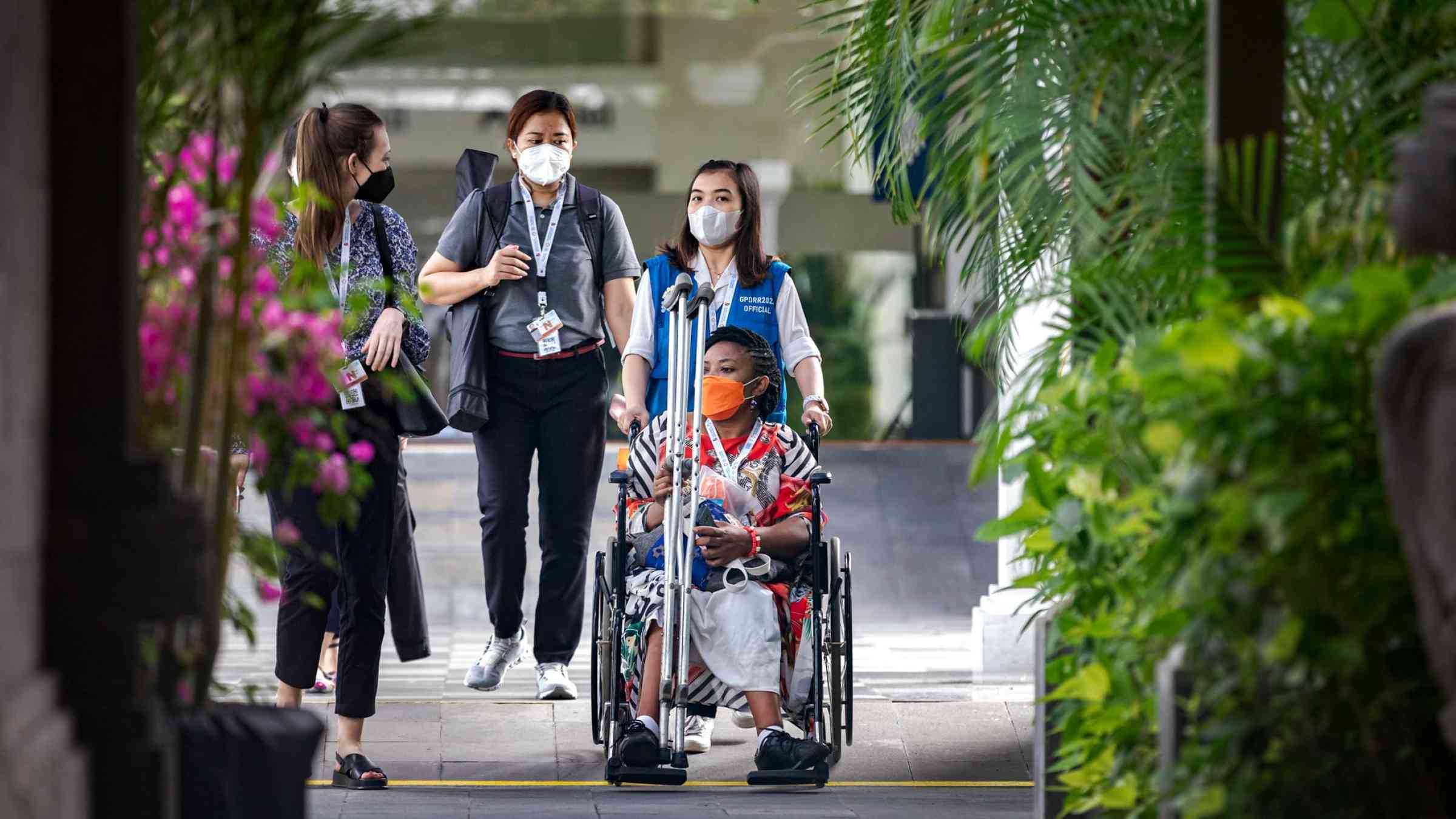 A woman being wheeled in a wheelchair at the 7th Global Platform for Disaster Risk Reduction, 27 May 2022, Bali, Indonesia