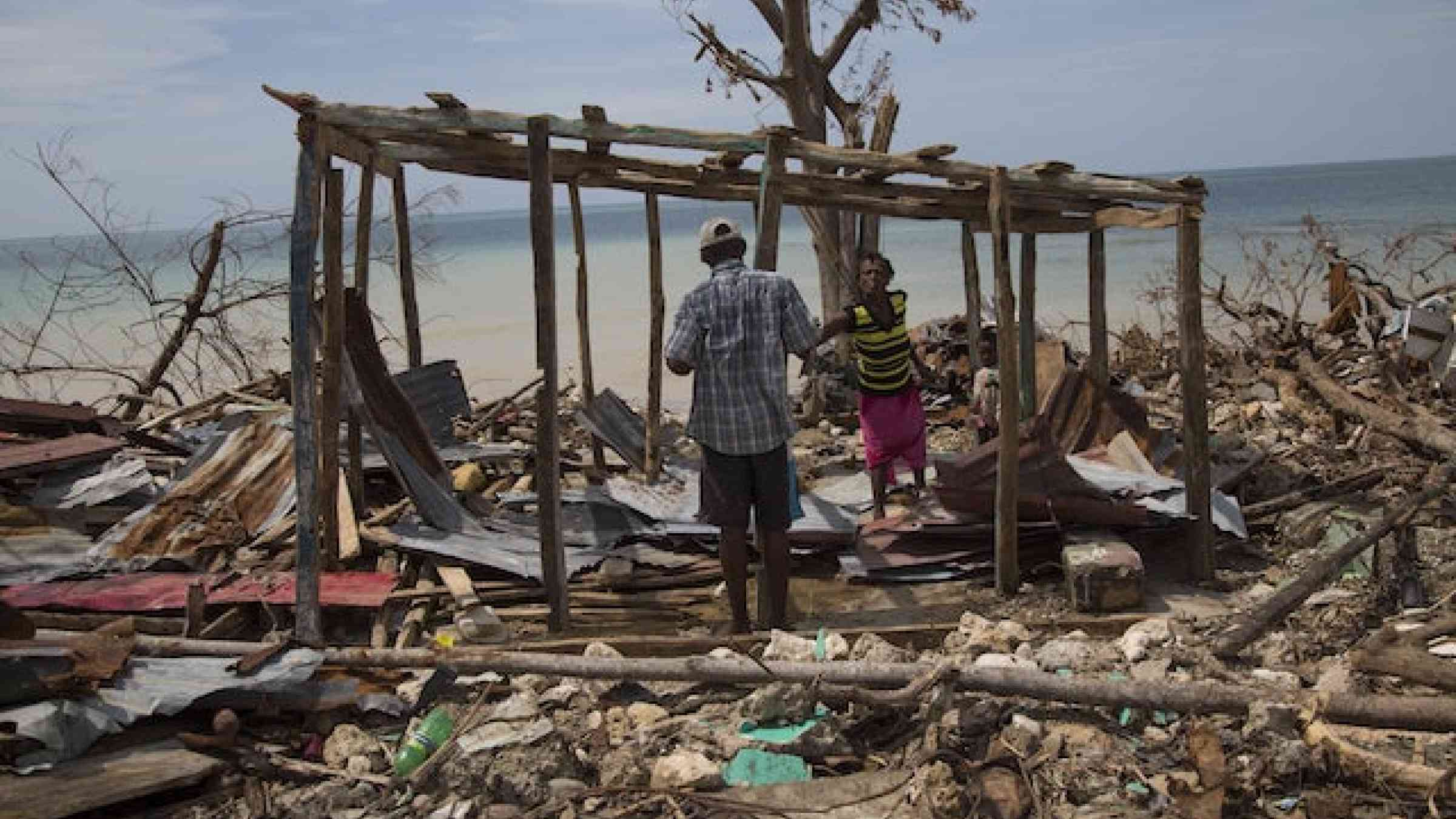People in a destroyed house following Hurricane Matthew in Roche a Bateux, Haiti in October 2016