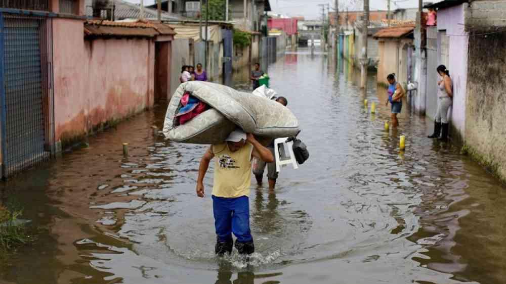 people carrying belongings in a flooded neighbourhood