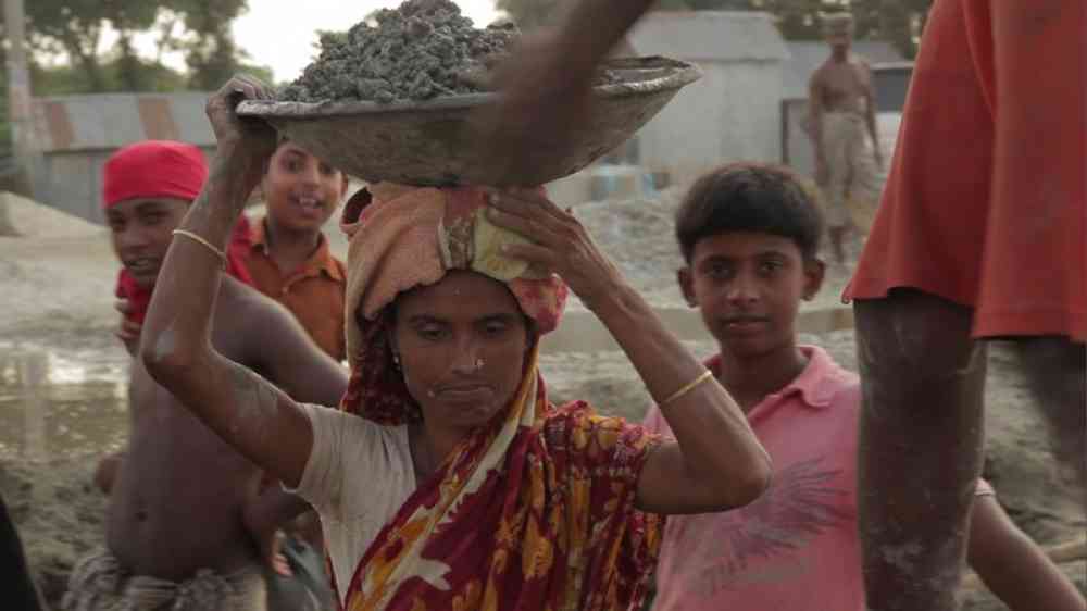 woman carrying mud in a pan on the head