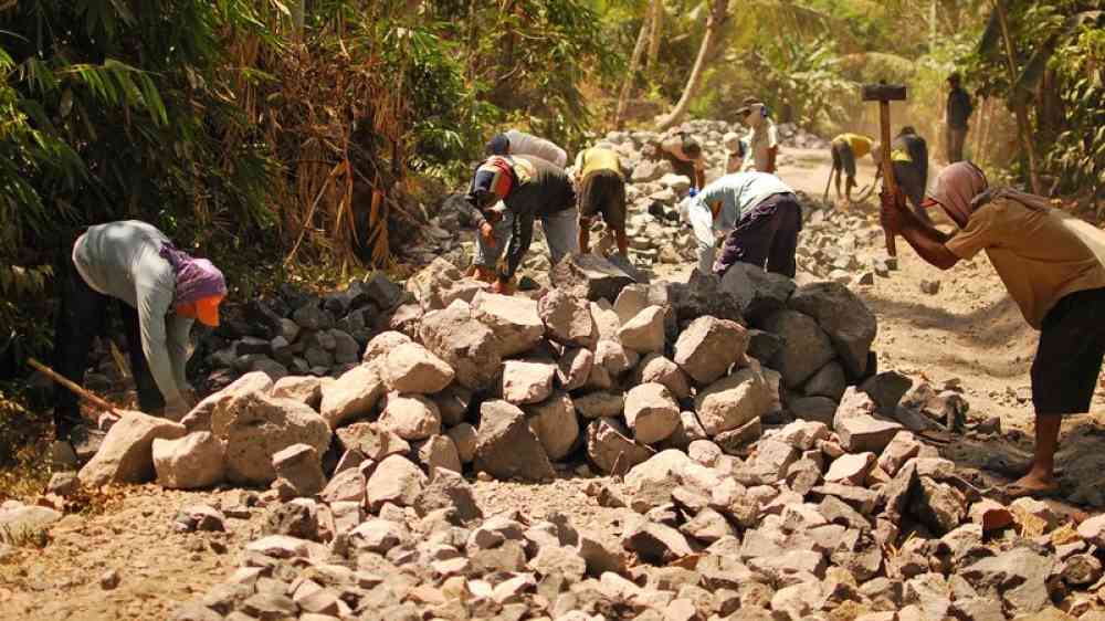 men breaking stones in a forest road