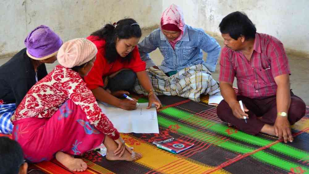 Group of people sitting on a carpet receiving training on Financial Education