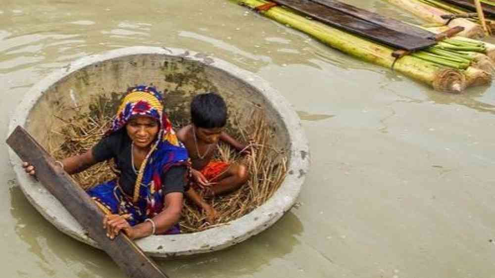 Woman and a child navigate the floodwater in Bangladesh