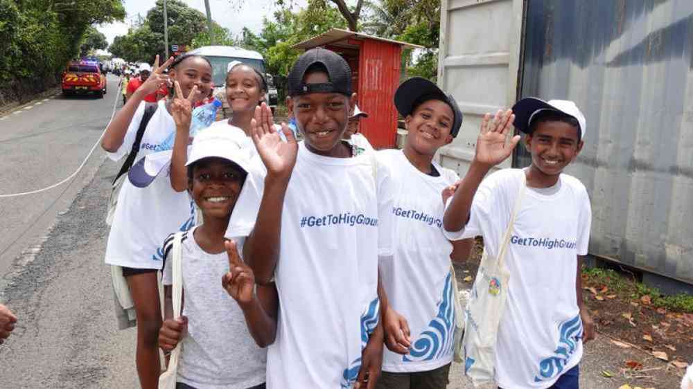 children waving and wearing a "get to high ground" project tshirt